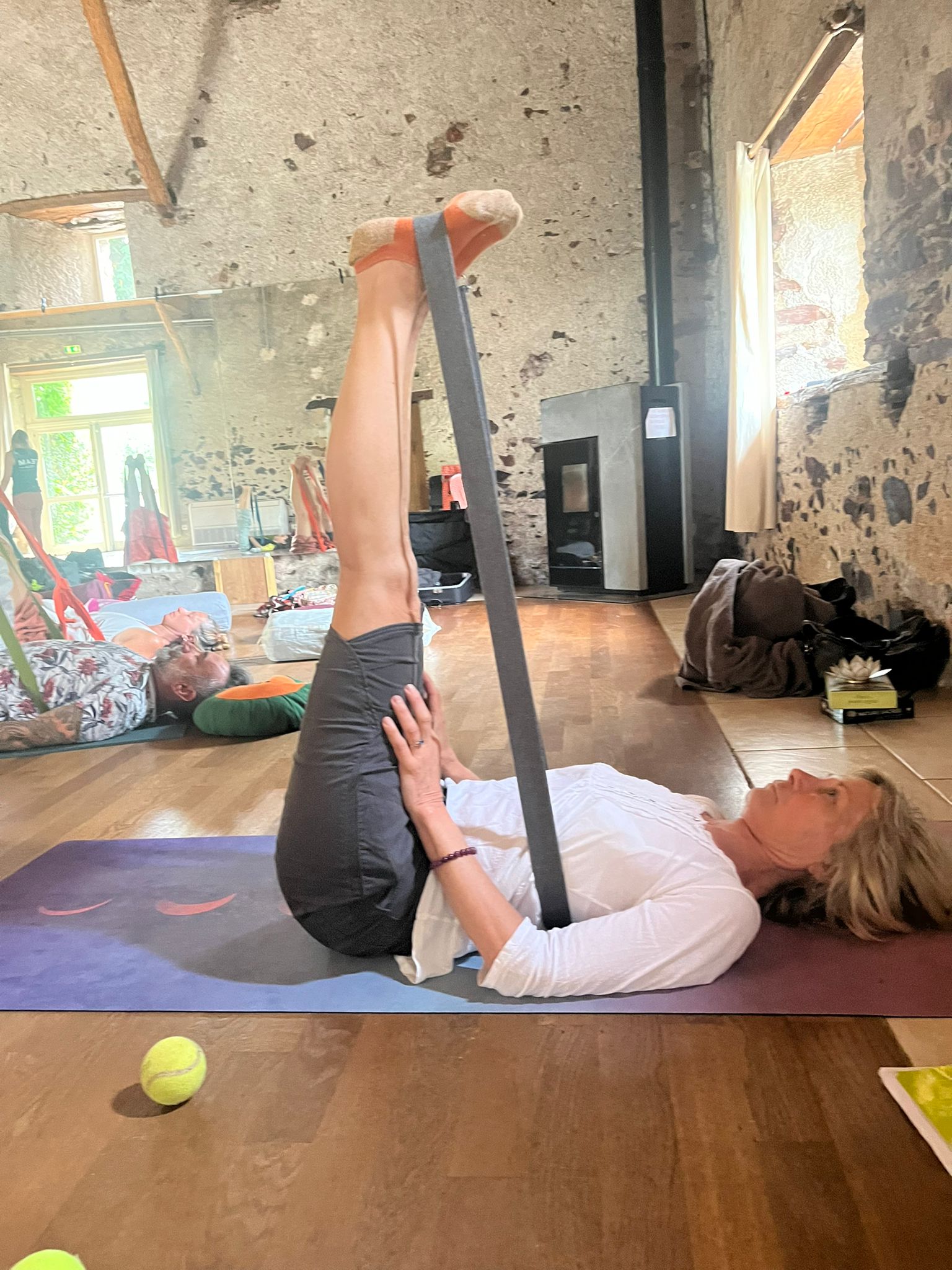 Étirement guidé à l'aide d'une sangle, pendant un stage de yoga