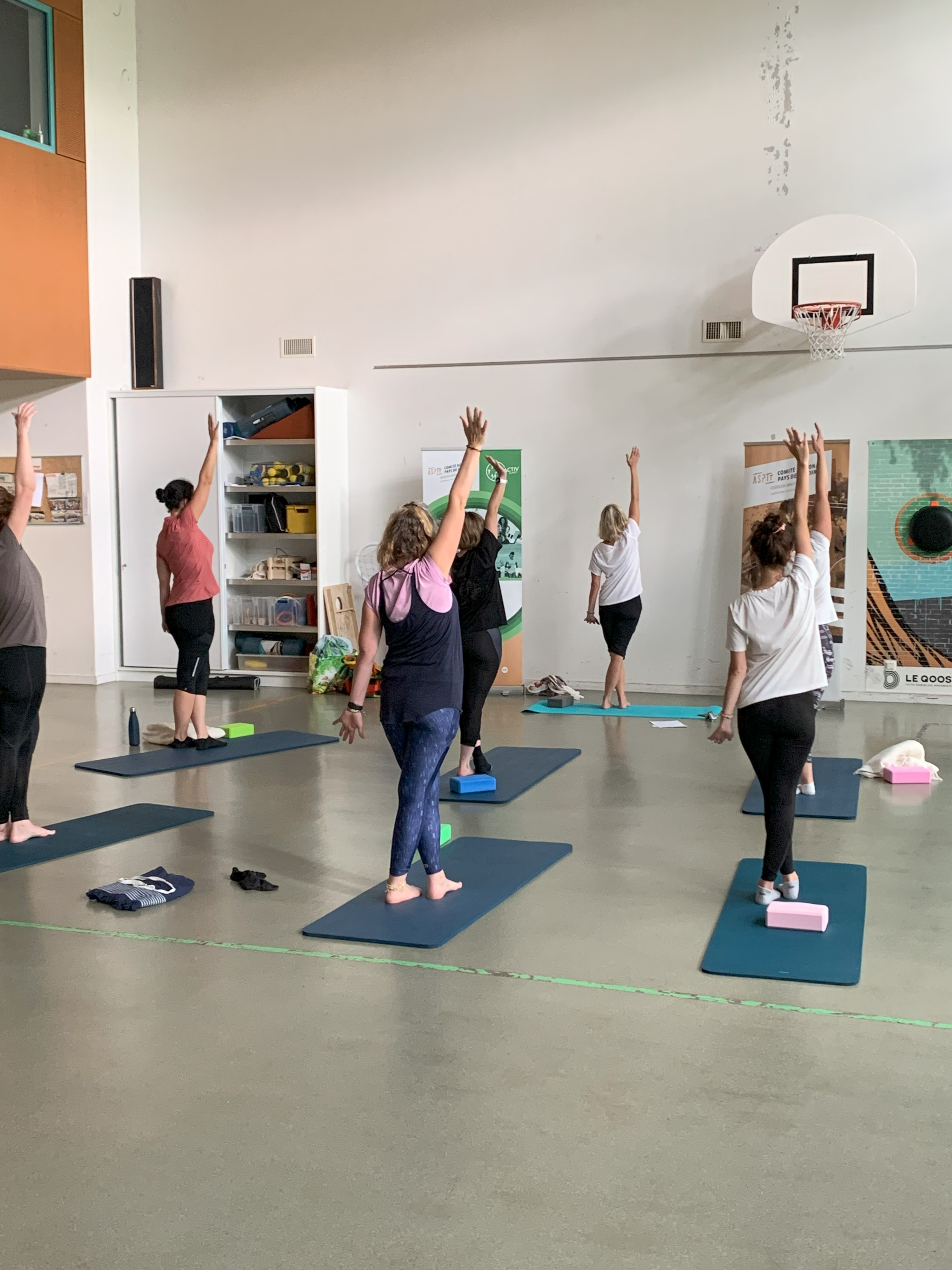 Cours collectif de yoga, posture debout bras levés