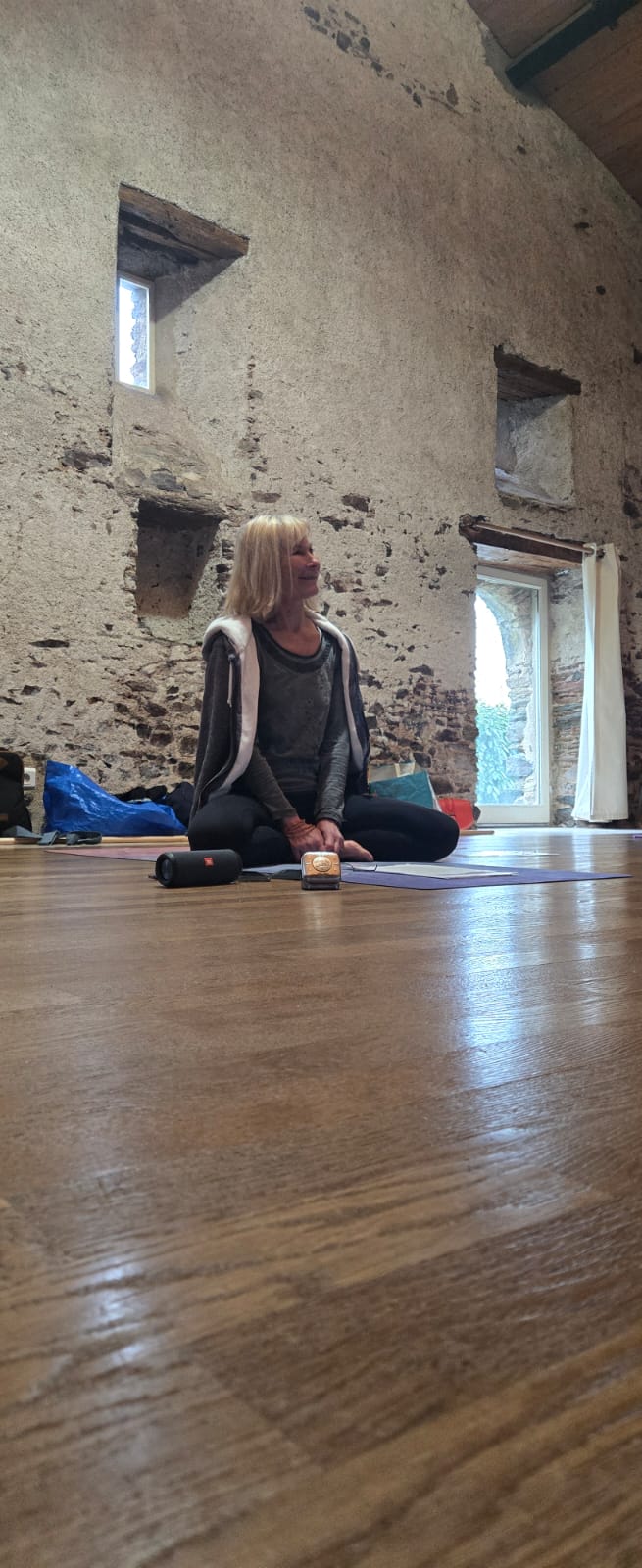 Chantal assise en méditation, dans une salle en pierre baignée de lumière, Angers